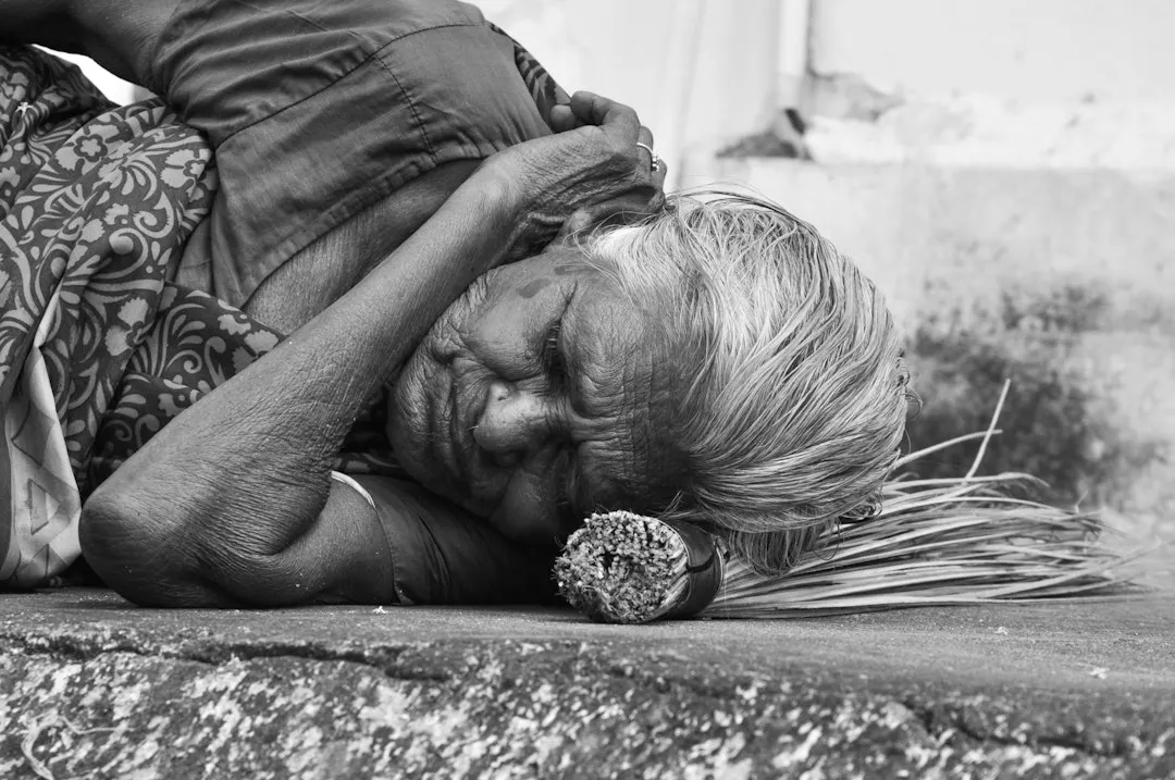women sleeping on a concrete surface grey-scale photography